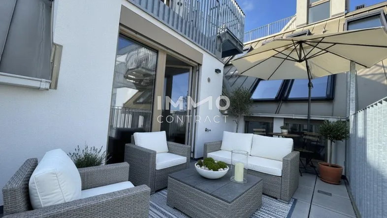 Geräumige Dachterrasse mit bequemen Loungemöbeln und Sonnenschirm, ideal zum Entspannen im Freien.