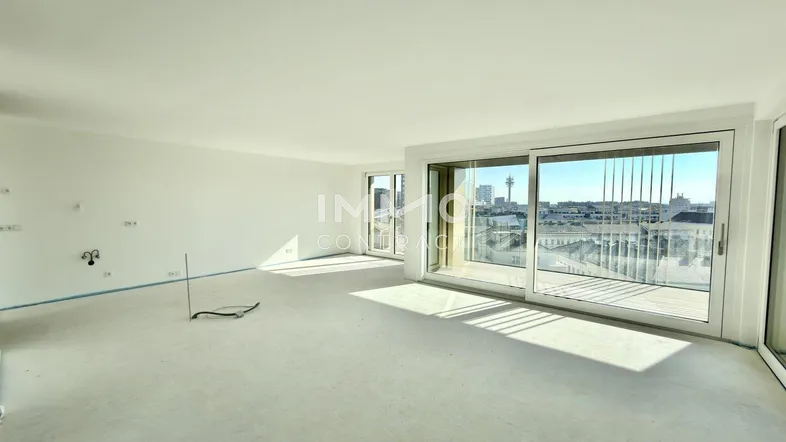 Heller, unmöblierter Wohnbereich im Rohbau mit großen Fenstern und Stadtblick.