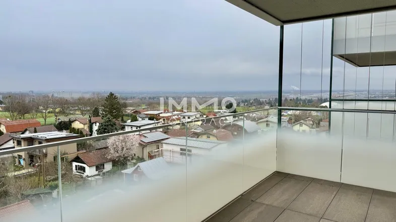 Geräumiger Balkon mit Glasbrüstung und weitem Blick über die umliegende Landschaft.