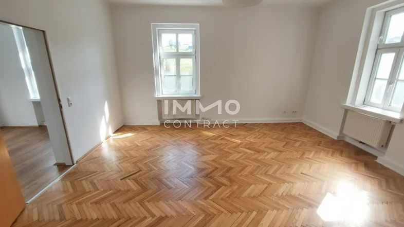 Helles Wohnzimmer mit Fischgrätparkettboden und Blick ins Grüne.