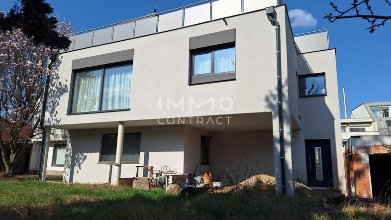 Rückansicht des modernen Wohnhauses mit Flachdach und großzügigen Fensterfronten.