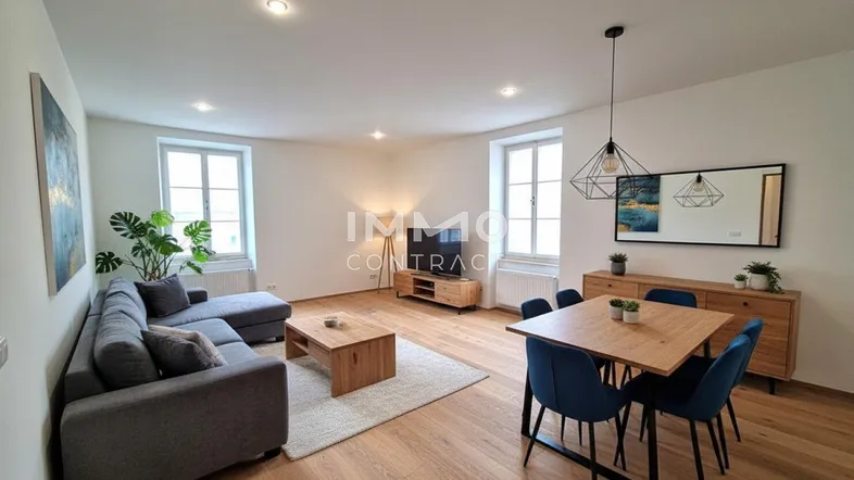 Heller Wohn- und Essbereich mit modernem Sofa, Holztisch und Parkettboden, ideal für geselliges Beisammensein.