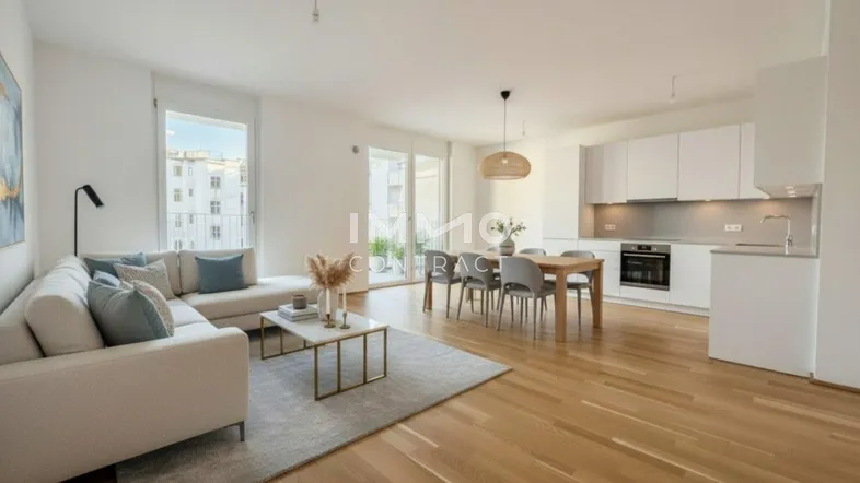 Helles, offenes Wohnzimmer mit integrierter Küche, Essbereich und Zugang zum Balkon.