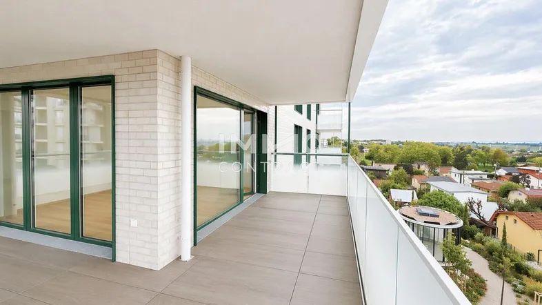 Geräumiger Balkon mit Fliesenboden, Glasgeländer und weitem Blick über die Umgebung.