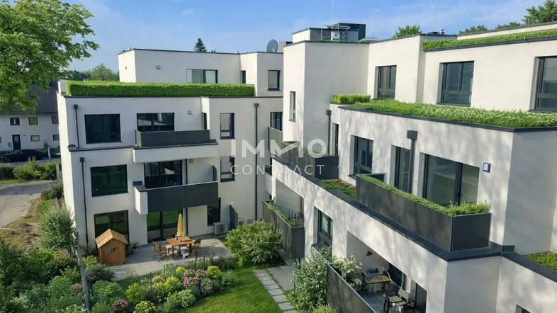 Moderne Wohnanlage mit mehreren Gebäuden, begrünten Dächern, Gärten und Balkonen.