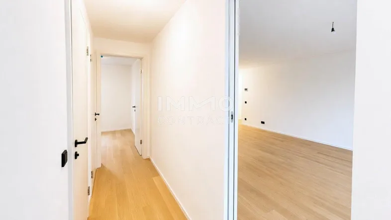 Heller Flur mit modernem Holzparkett und weißen Türen, der zu weiteren Räumen führt.