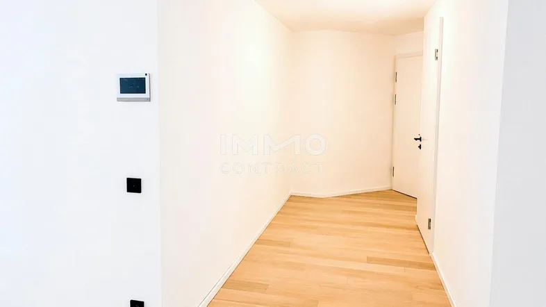Heller Flur mit modernem Parkettboden und weißen Wänden, der zu weiteren Räumen führt.