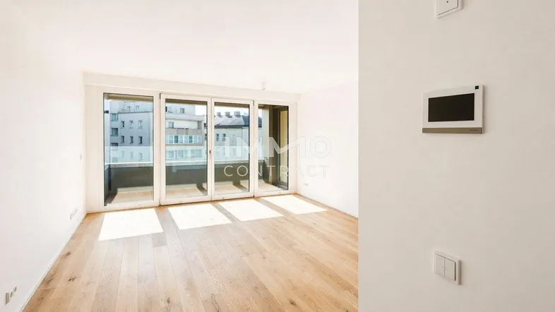 Helles Wohnzimmer mit Parkettboden und Zugang zu einem Balkon, ideal für modernes Wohnen.