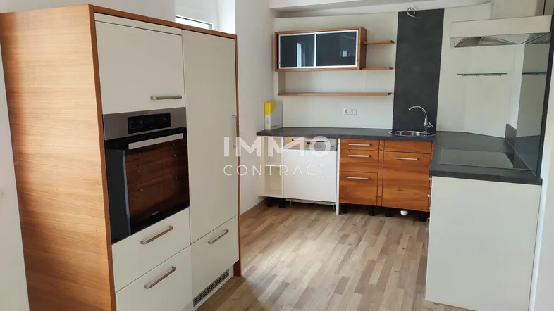 Moderne Einbauküche mit integriertem Backofen, hellen Fronten und Holzelementen.