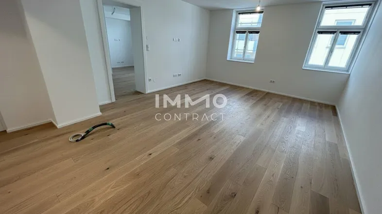 Helles Zimmer mit neuem Parkettboden und zwei Fenstern, bereit für die individuelle Gestaltung.