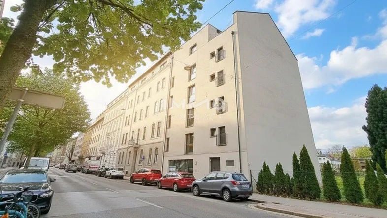 Mehrstöckiges Wohngebäude mit moderner Architektur und gepflegter Fassade an einer städtischen Straße.