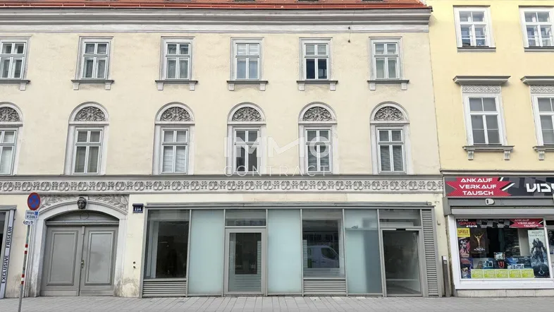 Historisches Gebäude mit klassischer Fassade und großen Schaufenstern im Erdgeschoss, gut gepflegt.