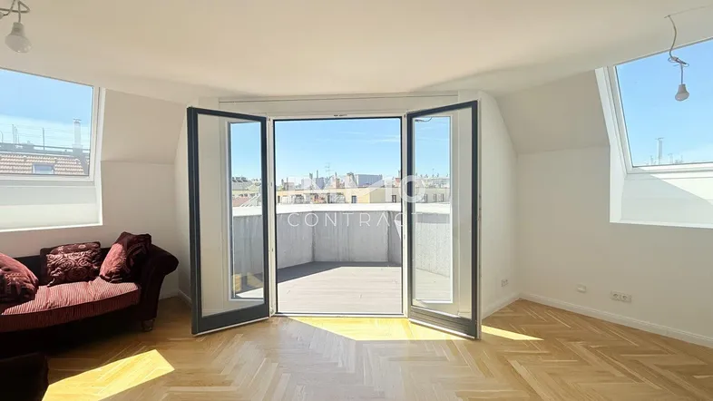 Helles Wohnzimmer mit Fischgrätparkett, Dachschrägen und Zugang zu einer Terrasse mit Stadtblick.
