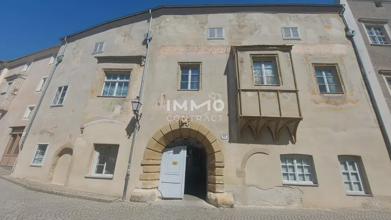 Altes Gebäude mit historischer Fassade und Erker an einer gepflasterten Straße.