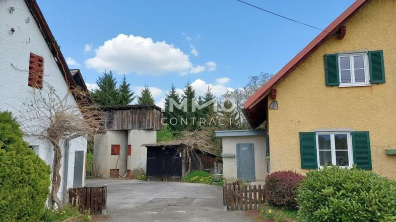 Ländliches Anwesen mit mehreren Gebäuden und einem Hof unter blauem Himmel.