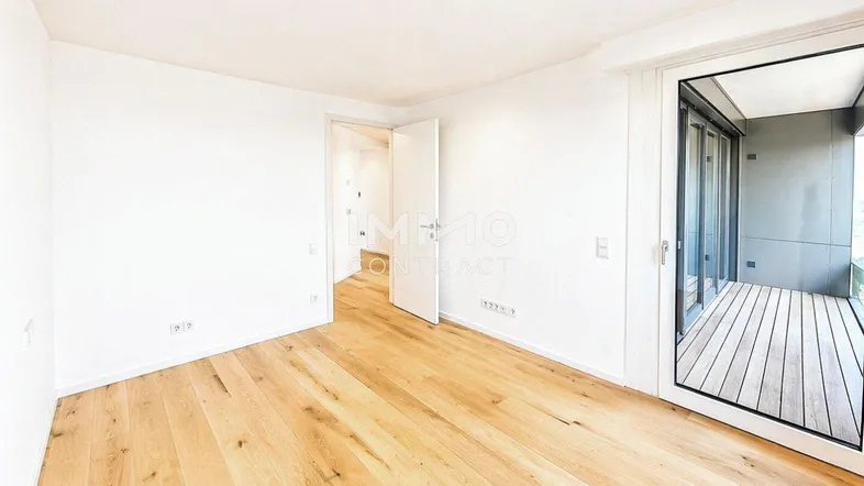Helles Zimmer mit Holzboden und Zugang zu einem Balkon, ideal als Schlafzimmer oder Wohnbereich.