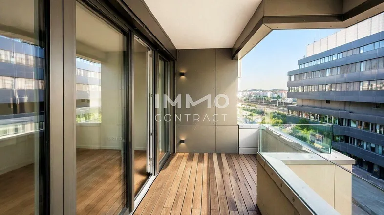 Geräumiger Balkon mit Holzboden und Glasgeländer, bietet einen weiten Blick auf die Umgebung.