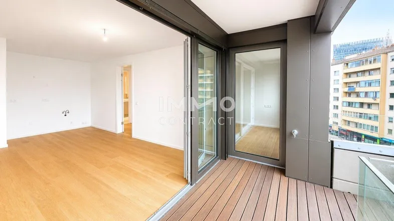 Helles Wohnzimmer mit Holzboden und Zugang zu einem Balkon mit Stadtblick.