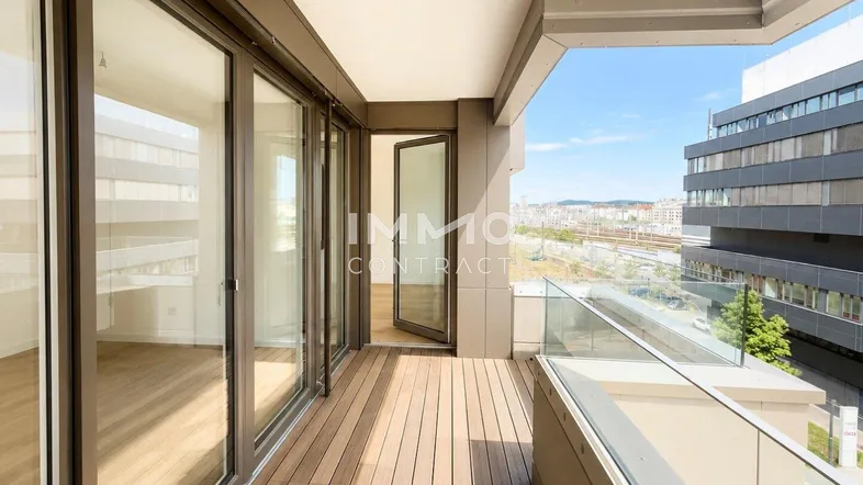 Geräumiger Balkon mit Holzboden und Glasgeländer bietet einen weiten Blick über die Stadt.
