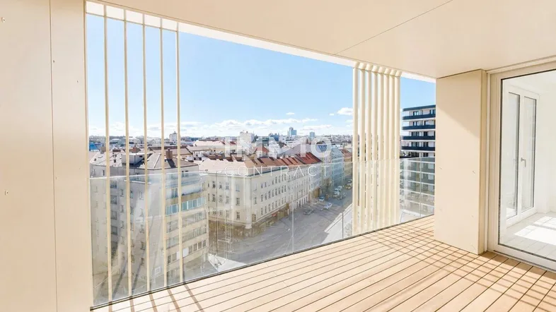 Geräumiger Balkon mit Holzboden, Glasgeländer und weitem Blick über die Stadt.