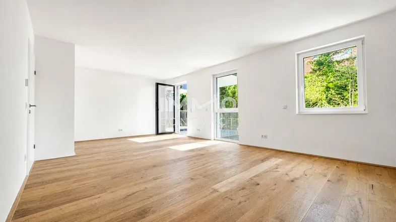 Helles, leeres Wohnzimmer mit Holzboden und Zugang zu einem Balkon, ideal für individuelle Gestaltung.
