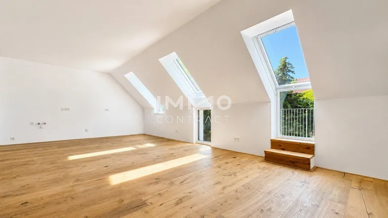Helles Dachgeschosszimmer mit Holzboden und mehreren Dachfenstern, die viel Tageslicht hereinlassen.