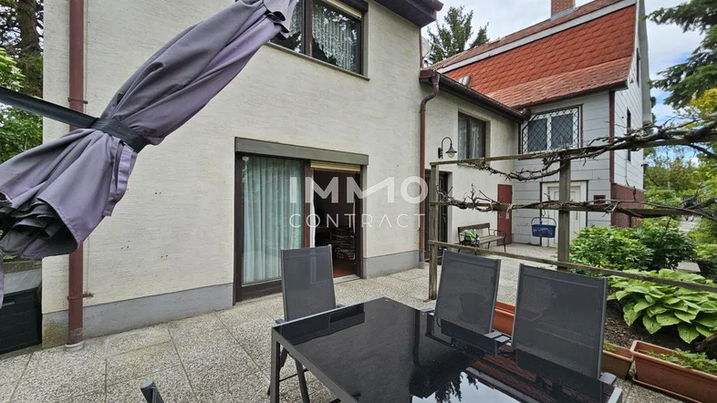 Geräumige Terrasse mit Esstisch und Sonnenschirm, ideal für Mahlzeiten im Freien.