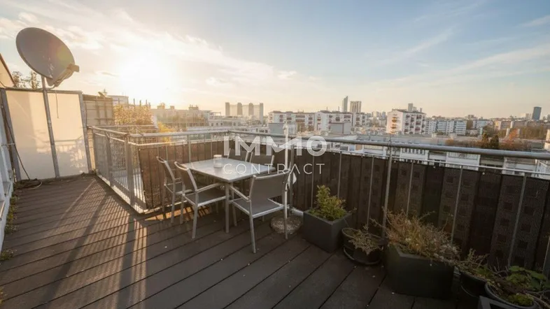 Große Dachterrasse mit Holzboden, Esstisch und weitem Blick über die Stadt bei Sonnenuntergang.