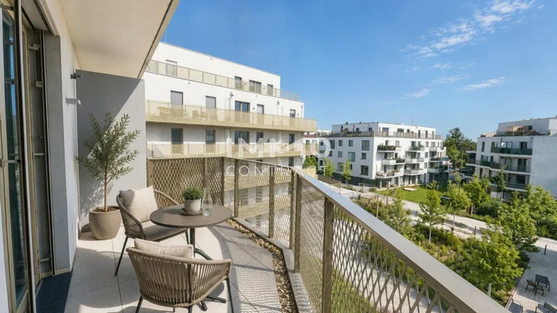 Möblierter Balkon mit Blick auf moderne Wohngebäude und grüne Außenanlagen.
