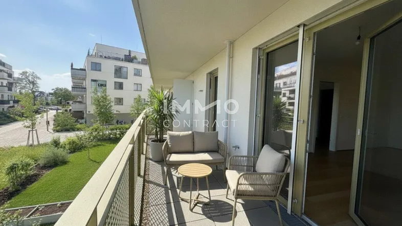 Möblierter Balkon mit Blick auf die grüne Umgebung und moderne Gebäude.