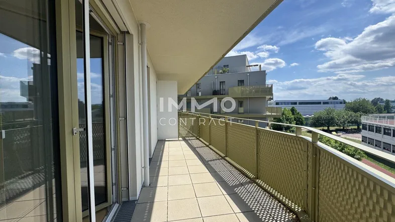 Geräumiger Balkon mit Fliesenboden und Blick auf die umliegenden Gebäude unter blauem Himmel.