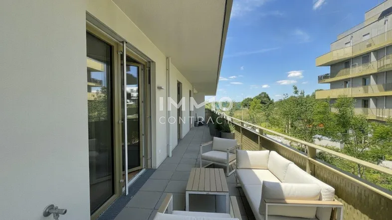 Langer Balkon mit modernen Outdoor-Möbeln und Blick ins Grüne, ideal zum Entspannen.