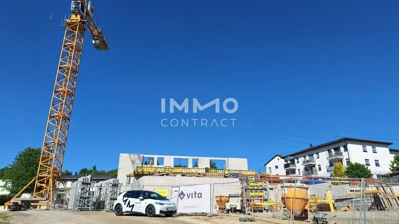 Baustelle mit gelbem Kran und im Bau befindlichem Gebäude unter strahlend blauem Himmel.