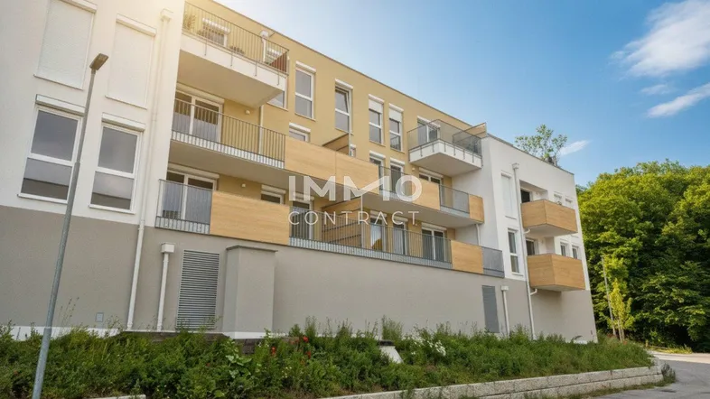 Moderne Wohnanlage mit mehreren Balkonen und heller Fassade unter blauem Himmel.