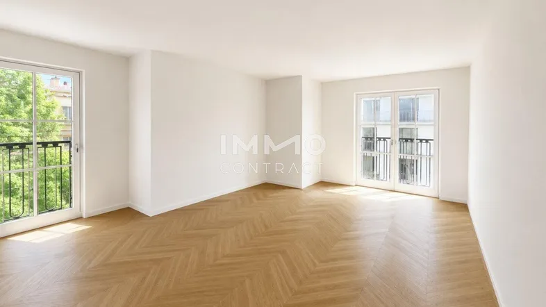 Helles, leeres Zimmer mit Fischgrätparkett und Zugang zu französischen Balkonen.