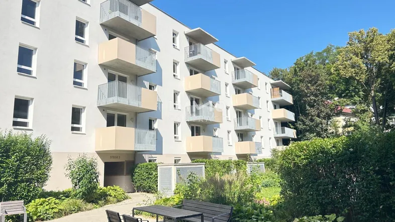 Moderne Wohnanlage mit mehreren Balkonen und gepflegter Grünfläche im Vordergrund.