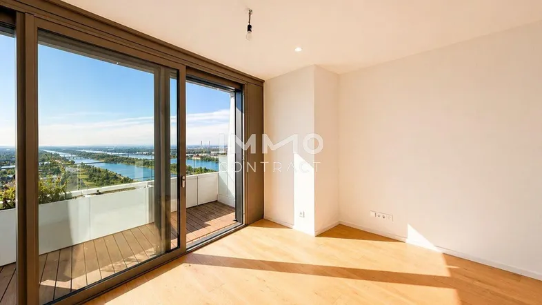 Helles Zimmer mit Holzboden und großen Schiebetüren, die zu einem Balkon mit Flussblick führen.