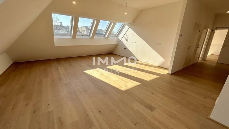 Helles Dachgeschosszimmer mit Holzboden und mehreren Dachfenstern, ideal als Wohn- oder Schlafbereich.