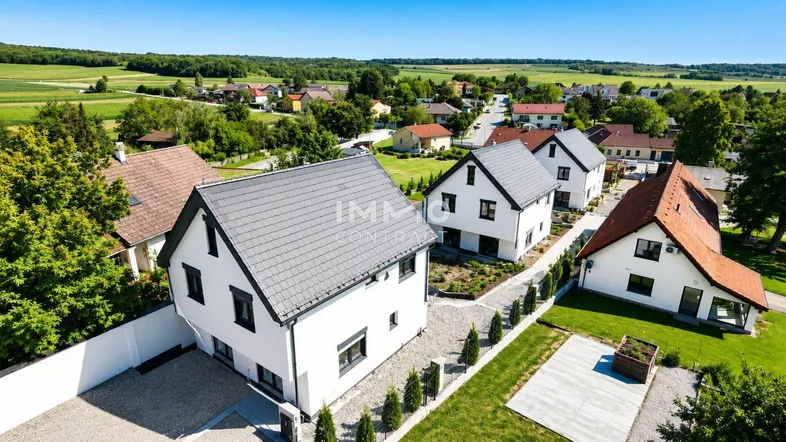 Luftaufnahme einer Siedlung mit modernen Einfamilienhäusern in ländlicher Umgebung.