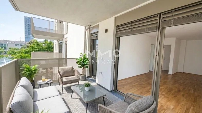 Möblierter Balkon mit bequemen Sitzgelegenheiten und Blick auf die Umgebung, verbunden mit einem hellen Innenraum.