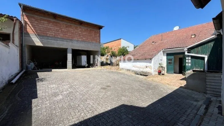 Gepflasterter Innenhof mit älterem Gebäude und einem Neubau im Hintergrund.