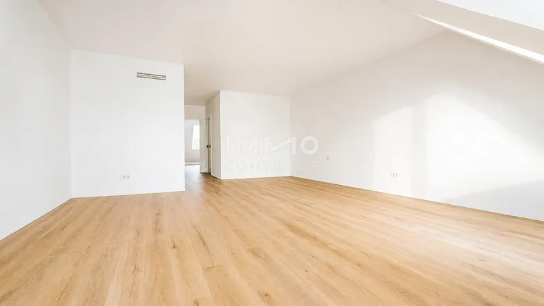 Helles, leeres Zimmer im Dachgeschoss mit modernem Laminatboden und weißen Wänden.