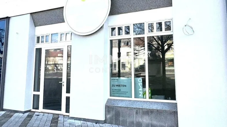 Moderne Geschäftsfassade mit großen Schaufenstern und Eingangstür auf Straßenniveau.