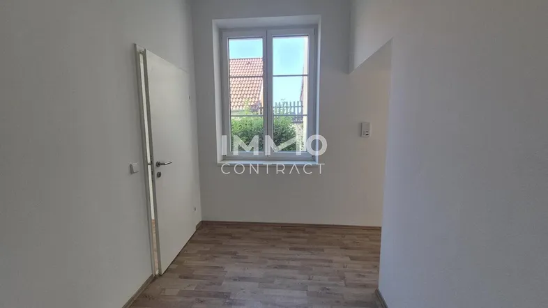 Helles Zimmer mit Laminatboden und Blick ins Grüne, ideal als Schlaf- oder Arbeitszimmer.