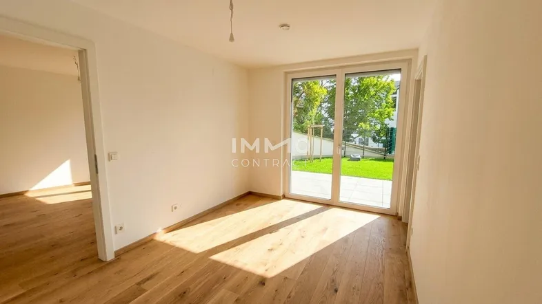Helles Zimmer mit Holzboden und direktem Zugang zum Garten durch große Schiebetüren.