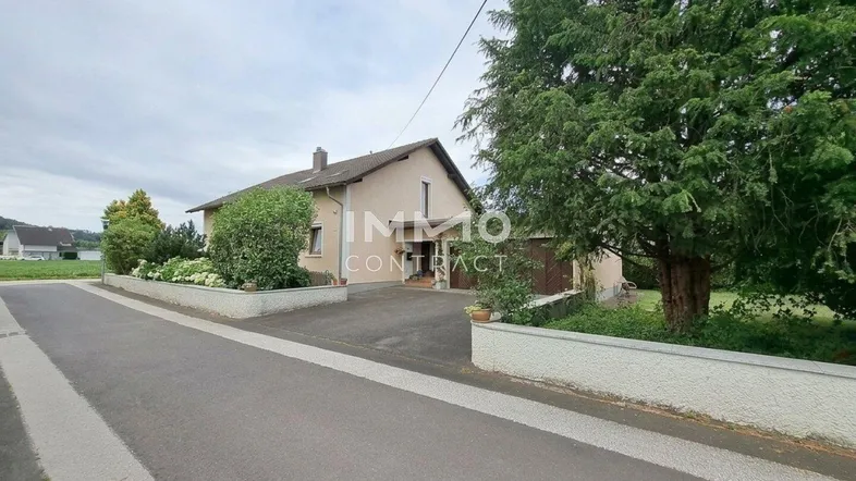 Das Haus präsentiert sich mit einer gepflegten Fassade, einer Einfahrt und umgebendem Grün in ländlicher Umgebung.