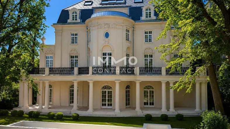 Prächtige Villa mit klassischer Architektur, umgeben von altem Baumbestand und einem gepflegten Garten.
