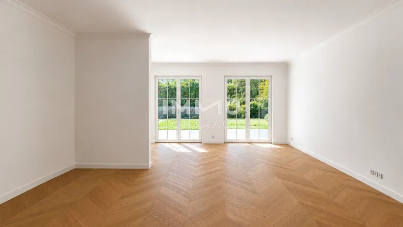 Helles Wohnzimmer mit Fischgrätparkett und großen Fenstertüren zum Gartenblick.
