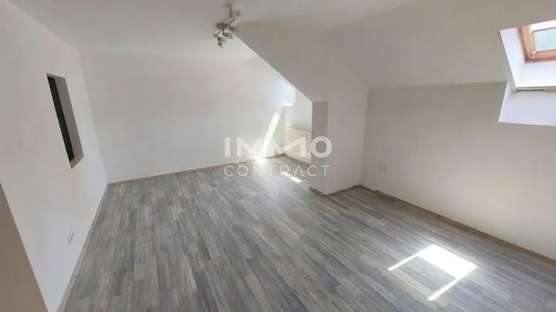 Helles Dachgeschosszimmer mit Laminatboden und Dachfenstern, ideal als Wohn- oder Schlafbereich.