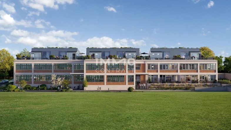 Moderne Wohnanlage mit großen Fenstern und Dachterrassen, umgeben von Grünflächen unter blauem Himmel.
